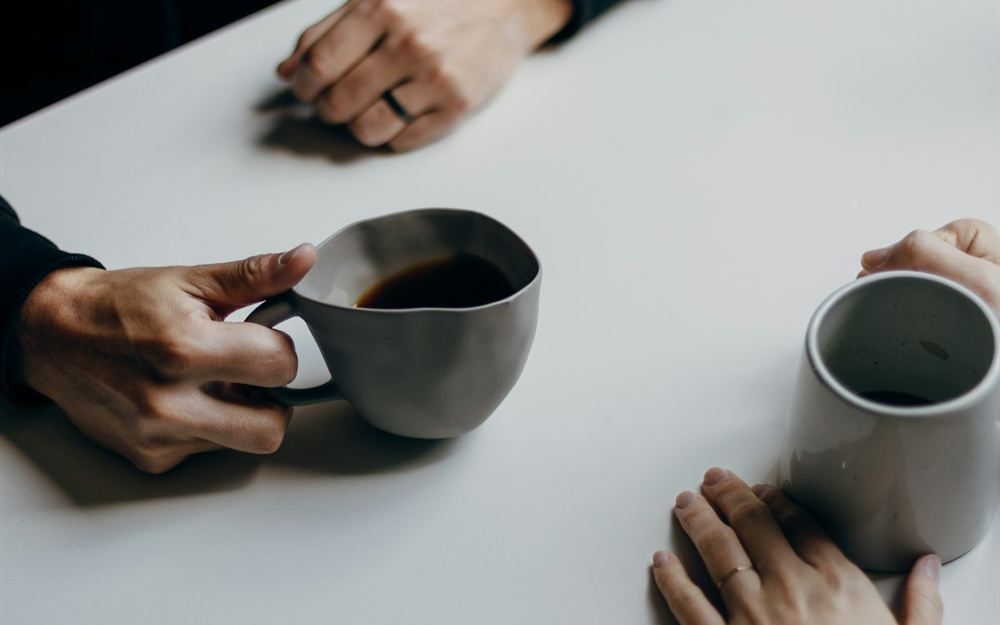テーブルでコーヒーカップを持つ手元